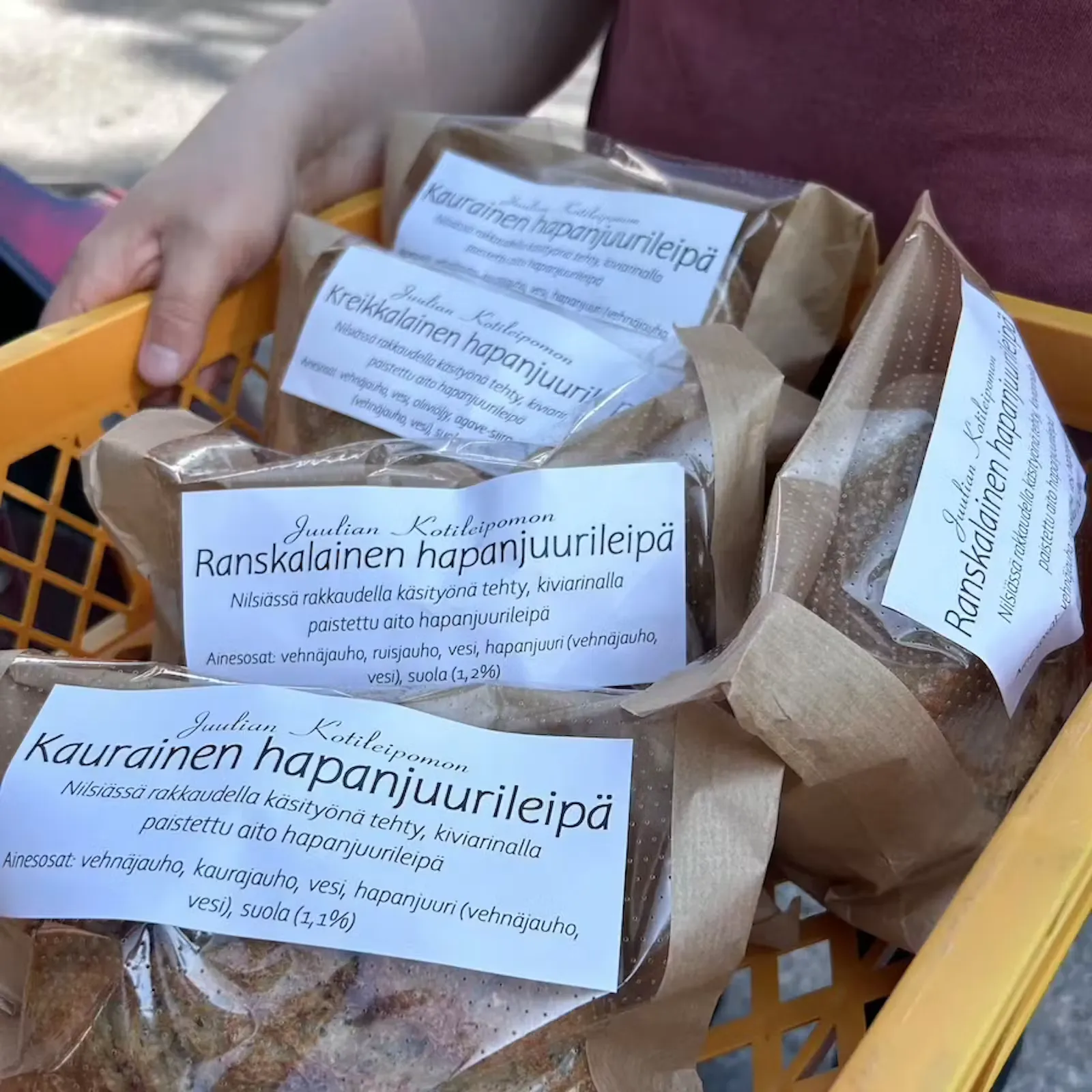 Juulian Kotileipomon pakatut hapanjuurileivät asiakkaan käsissä myyntipisteellä